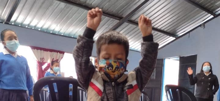 Young boy worshiping with hands raised and eyes closed at a Vida school
