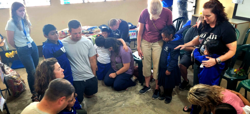 Mission Team praying for sponsor class