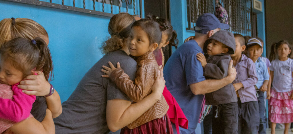 Guatemalan children receiving hugs from members of a missions team