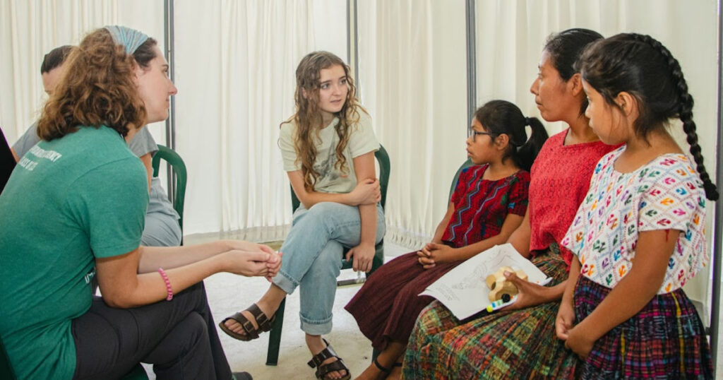Volunteer translator translating between medical volunteer and Guatemalan mother with two children